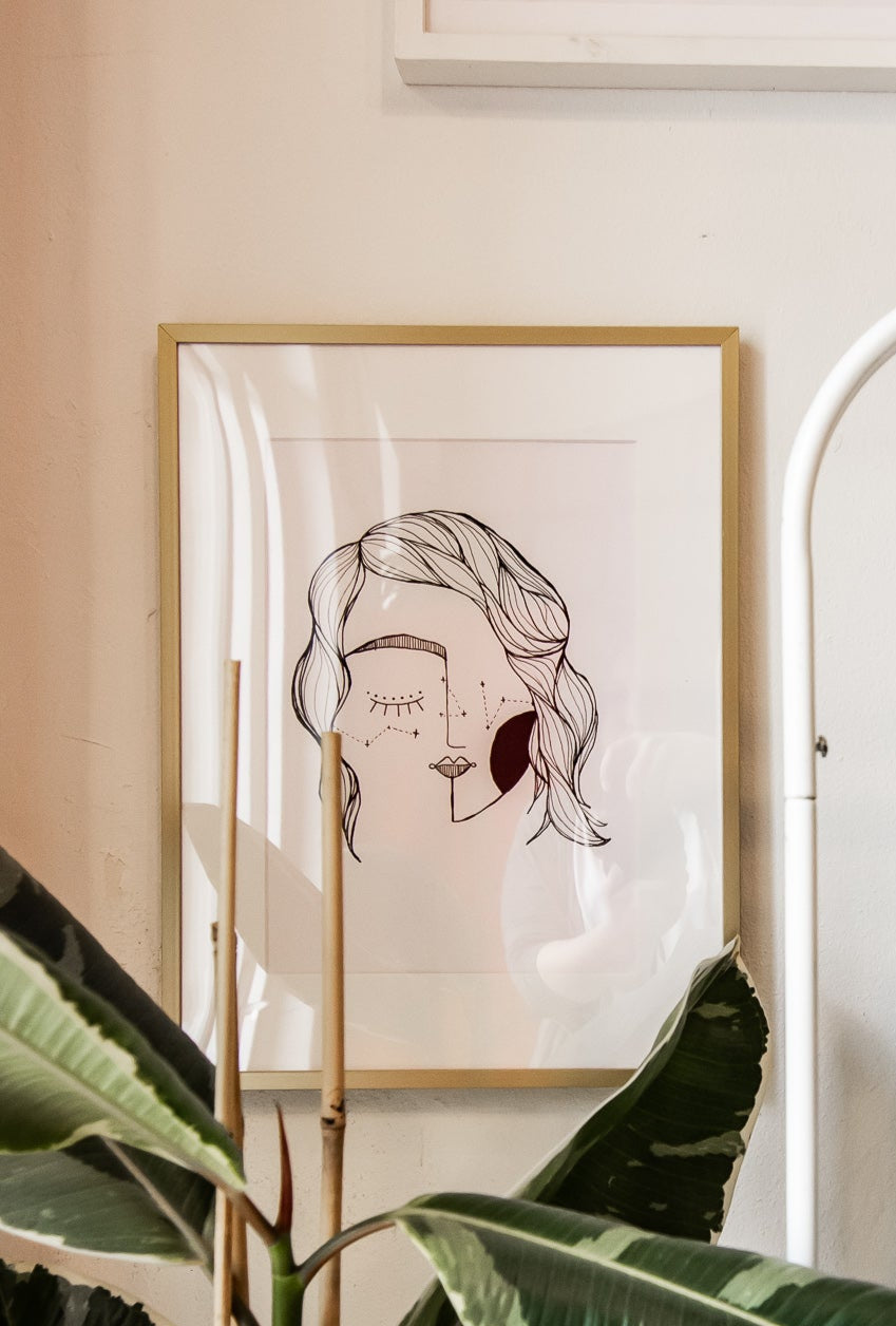 Room interior with a plant, framed art, and clothing rack.